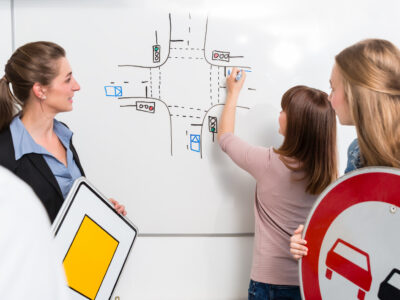 Learner in driving lessons theory explaining traffic situation on white board